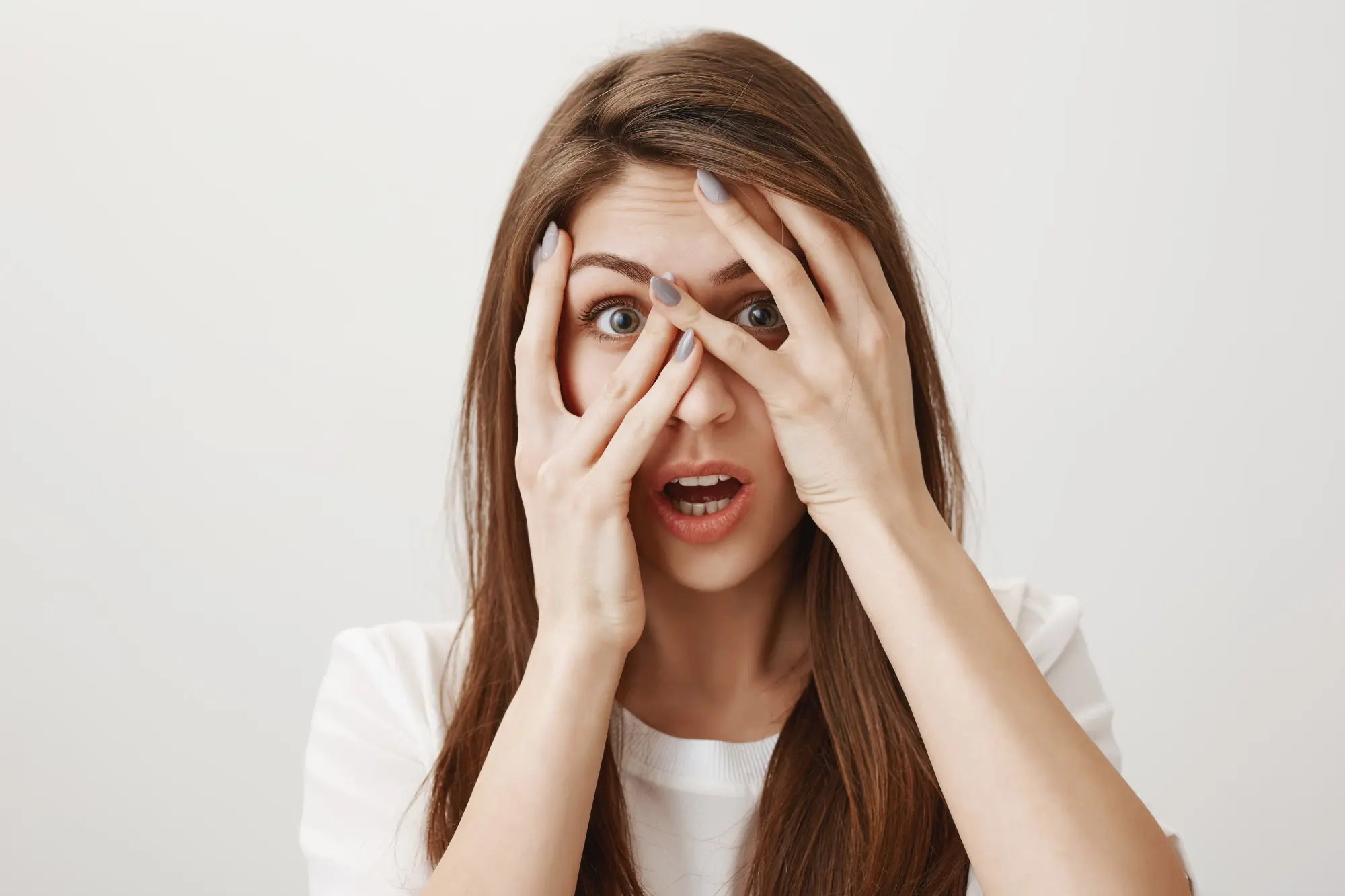 shocked-woman-peeking-through-fingers-with-startled-face