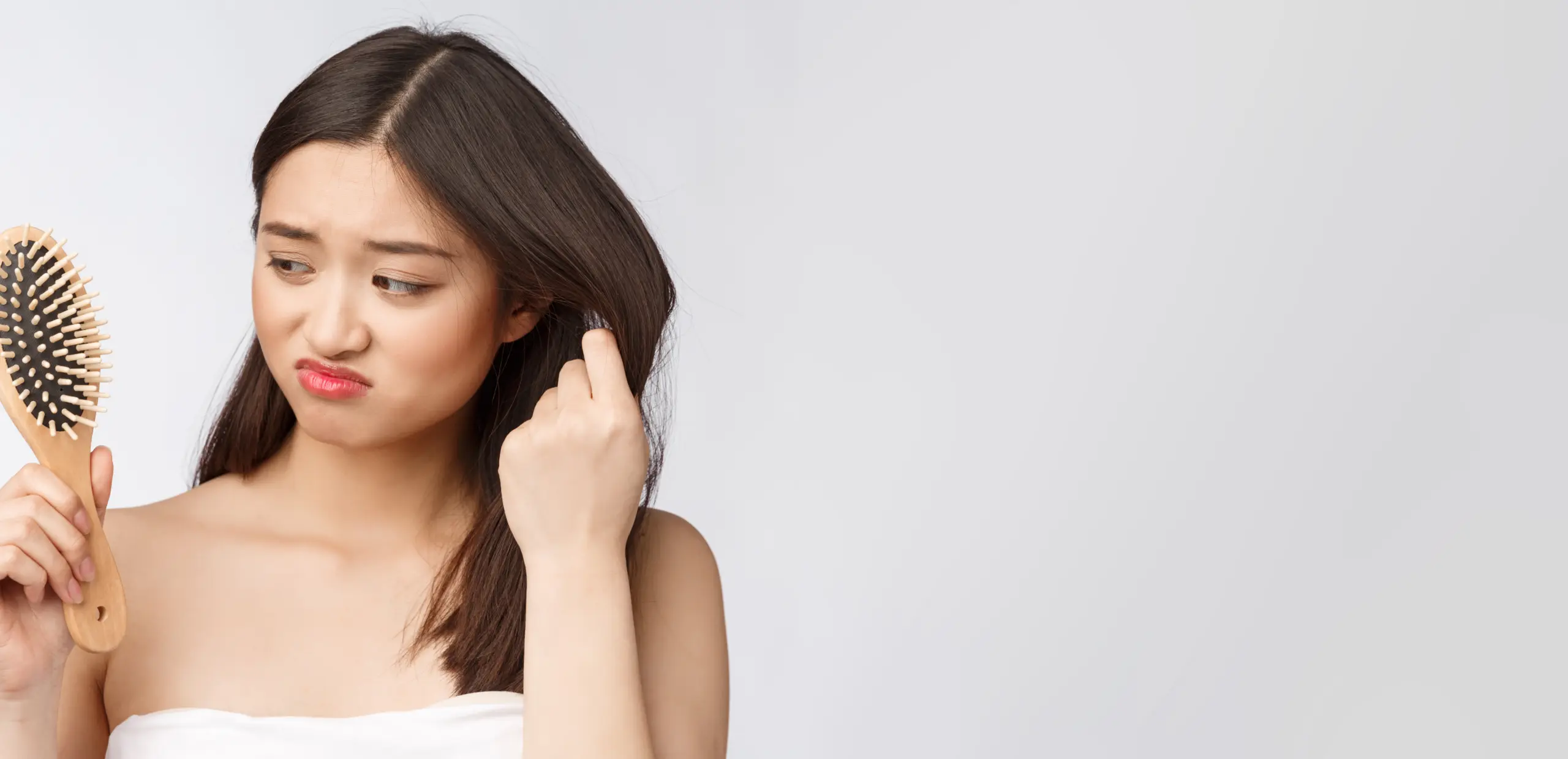 upset-stressed-young-asian-woman-holding-damaged-dry-hair-hands-white-isolated-background