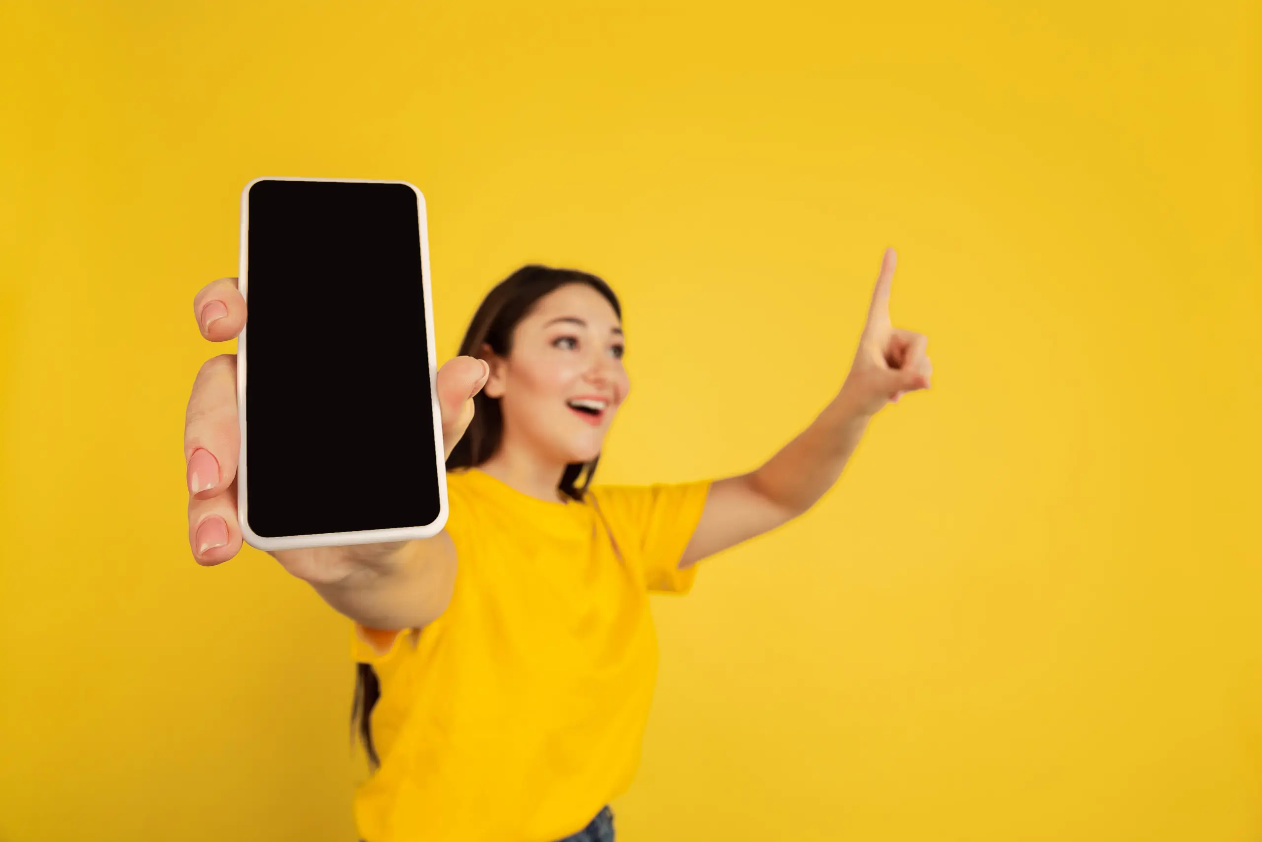 showing-blank-phone-s-screen-caucasian-woman-s-portrait-isolated-yellow-studio-background-beautiful-brunette-model-casual-concept-human-emotions-facial-expression-sales-ad-copyspace-min